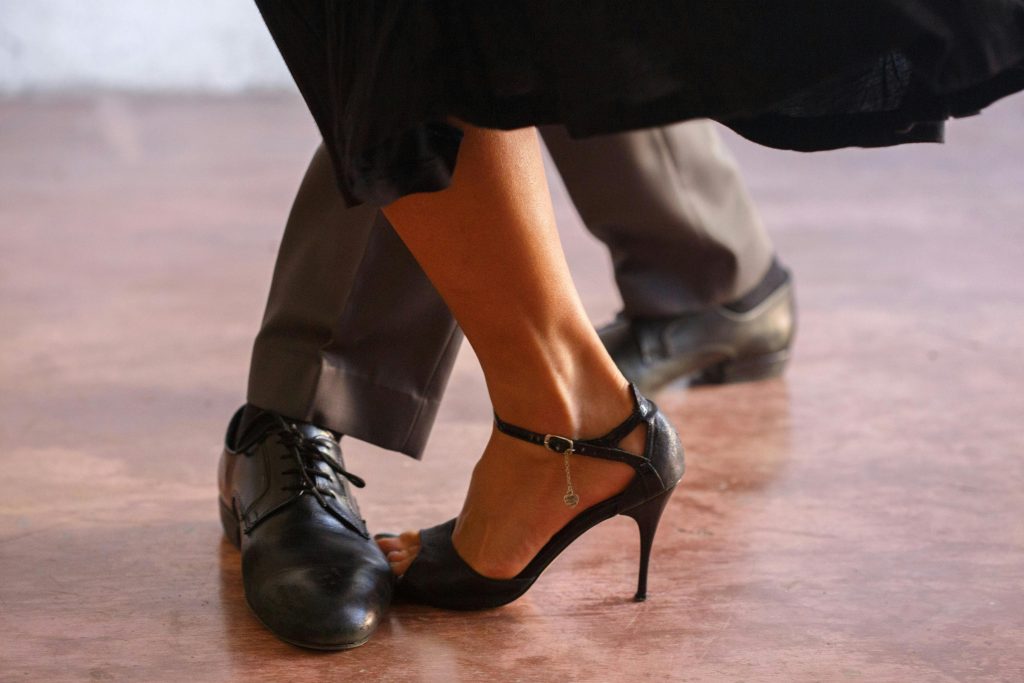 Close-up of a couple dancing tango, highlighting elegance in black shoes and high heels.